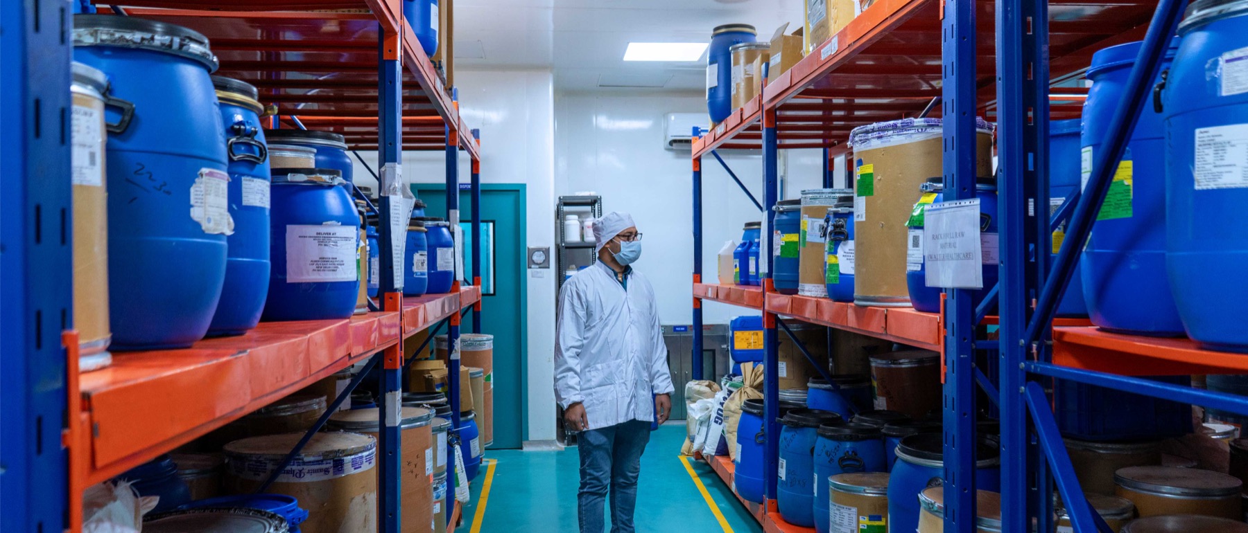 Cropped view of a team member inspecting identified containers along the central raw-material store aisle